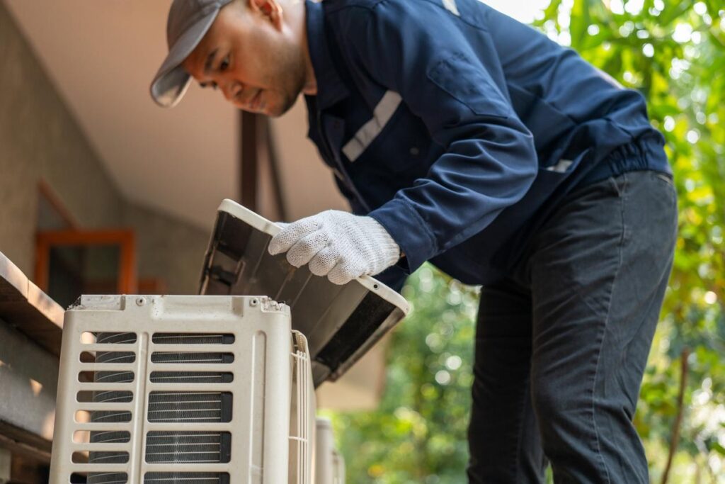 A technician puts a cover back on an air conditioning unit.